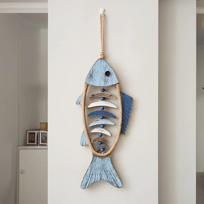 Decorative fish wall hanging with blue and wooden elements on a white wall. boho home decor, coastal home accents, nautical wall hanging, wooden fish wall decor, Mediterranean decor, beach house decoration, rustic fish ornament, vintage boho living room decor, seaside wall art, summer housewarming gift
