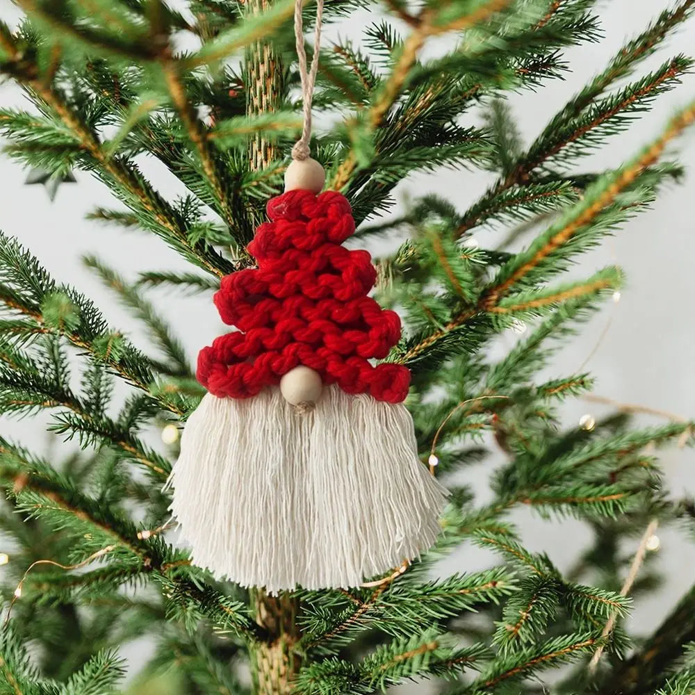 Decorative gnome macrame ornament with a red hat and white beard hanging on a Christmas tree.