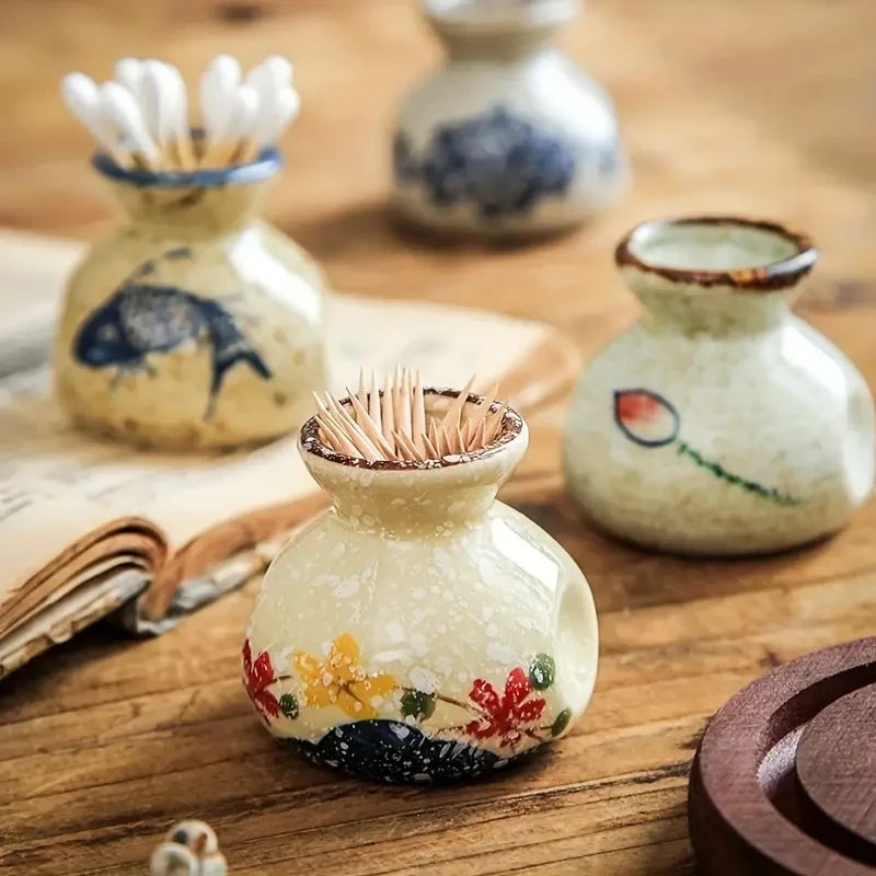 Decorative ceramic toothpick holders with floral designs on a wooden surface.