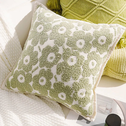 Green patterned pillow on a white surface with a yellow textured pillow in the background.