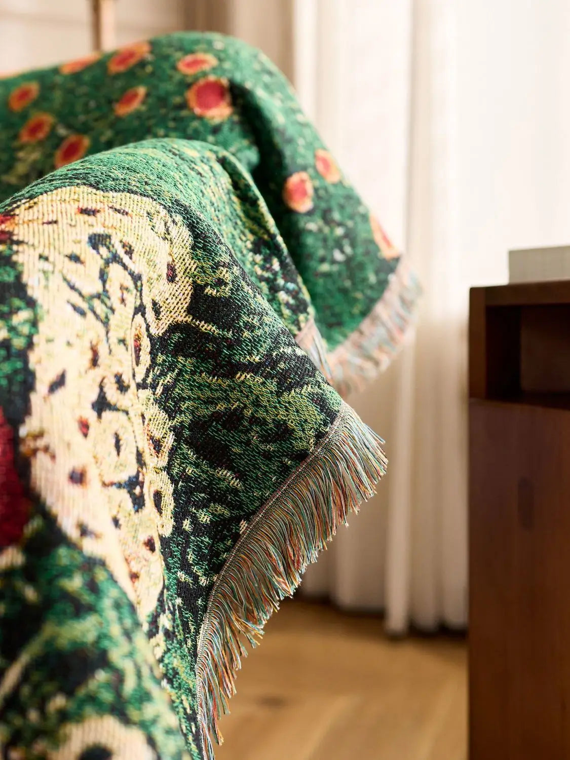 Decorative green blanket with floral patterns draped over a chair in a room. Cat woven throw blanket for boho sofa and home decor