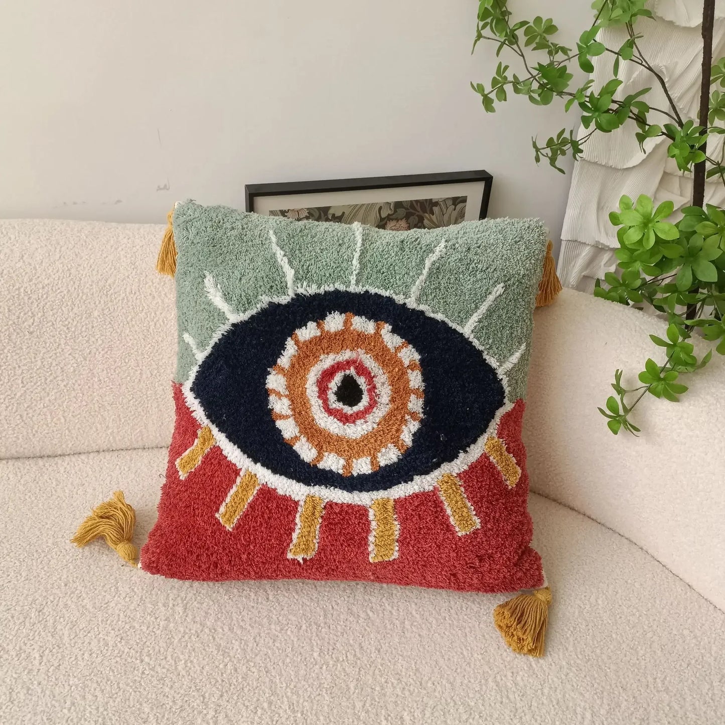 Decorative pillow with eye design on a couch next to a plant Boho Devil's Eye embroidered pillow cover with tufted geometric design in cotton blend fabric, decorative cushion for sofa, bed, or living room boho home decor.
