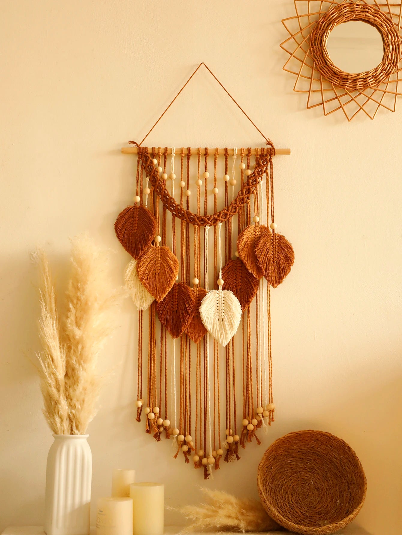 Woven leaf macrame wall hanging with decorative elements on a beige wall.