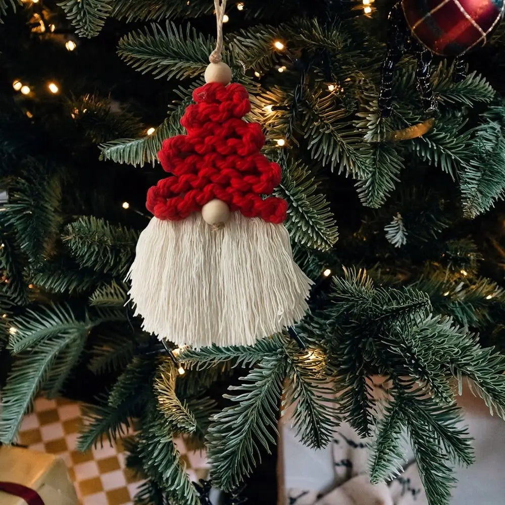 Decorative gnome macrame ornament with red hat and white beard hanging on a Christmas tree.