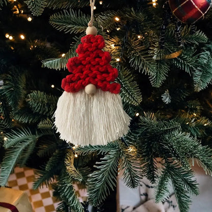 Decorative gnome macrame ornament with red hat and white beard hanging on a Christmas tree.