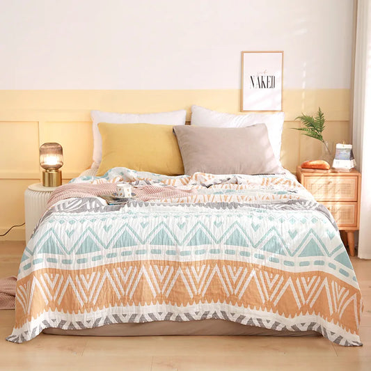 Bed with patterned quilt and pillows in a bedroom setting. Boho Lightweight microfiber summer blanket for bed or sofa, cooling breathable throw for home, dorm, or office naps with geometric jacquard pattern.