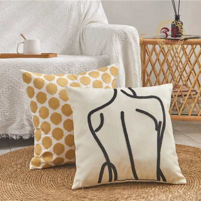 Two decorative pillows on a couch with a polka dot pattern and abstract design.