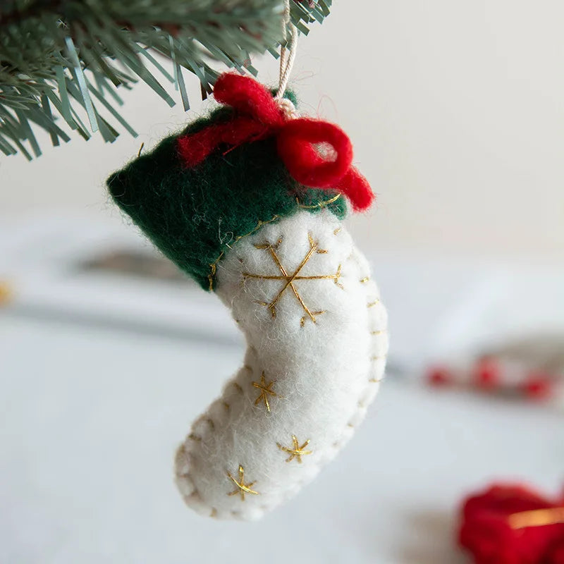Christmas stocking ornament with red bow hanging on a tree branch.