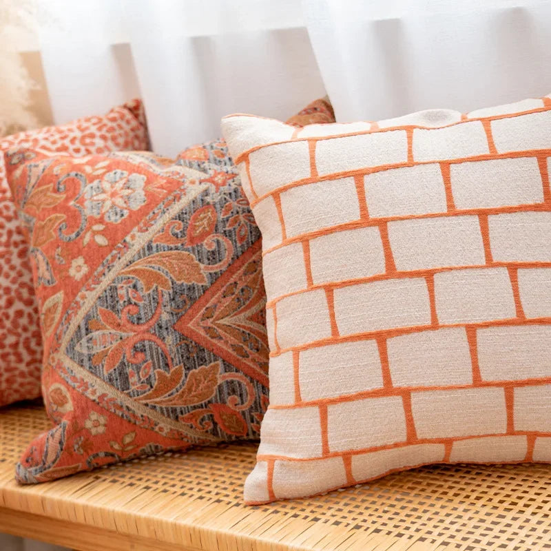 Decorative pillows with orange and beige patterns on a wicker surface.