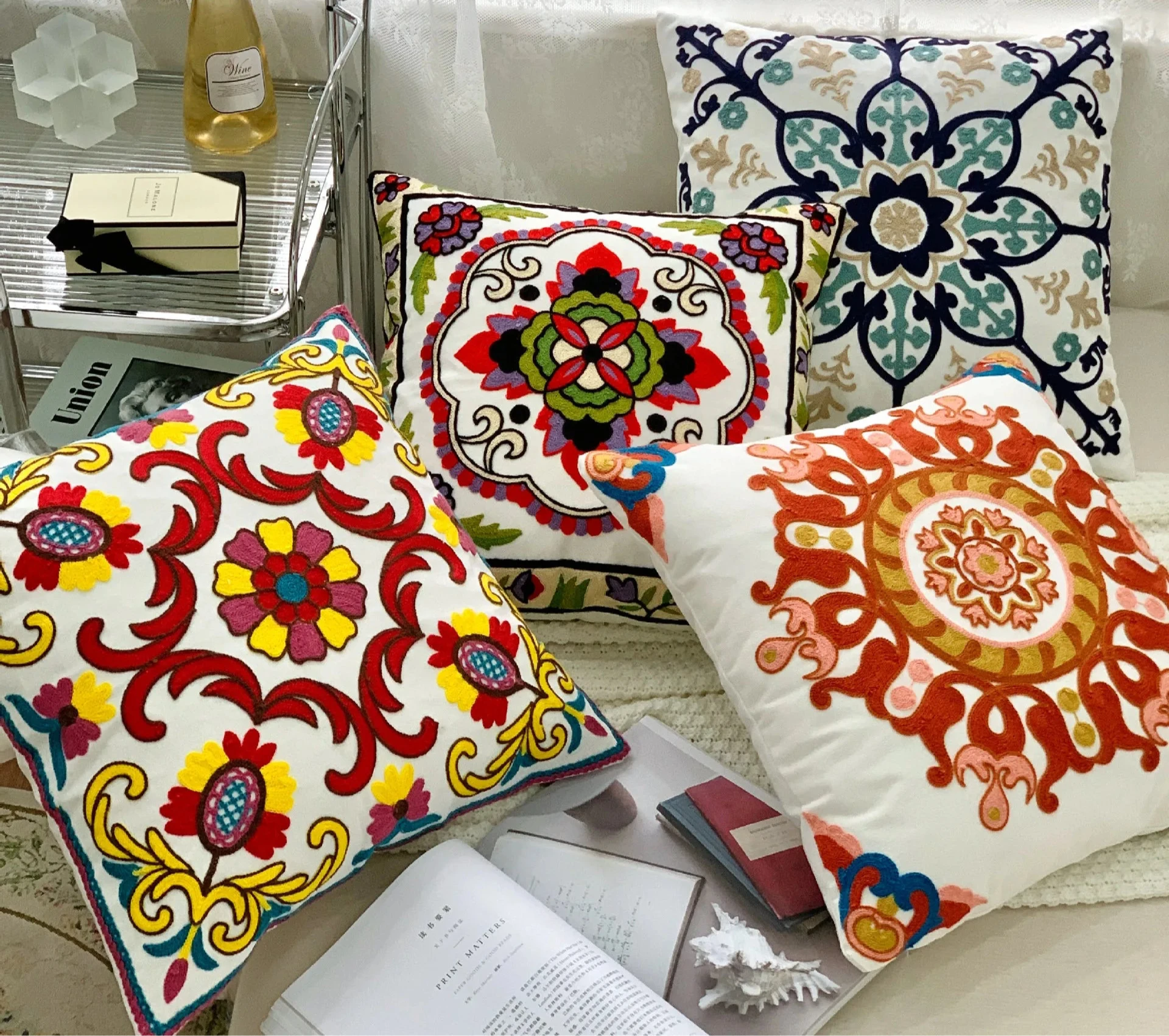 Decorative pillows with colorful patterns on a couch, featuring the brand Handcrafted embroidered cushion cover on armchair – modern boho living room decor