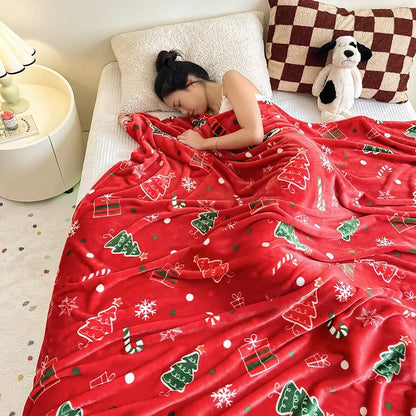 Person lying on a bed under a red Christmas-themed blanket
