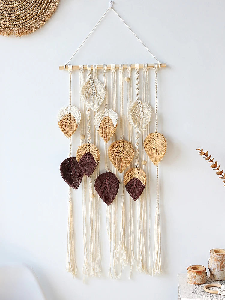 Decorative boho macrame wall hanging with leaf-shaped beads and tassels on a white background