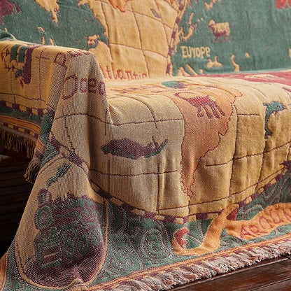 Map-themed quilt draped over a couch with world map design. Travel-inspired cotton plaid bed cover and decorative boho blanket