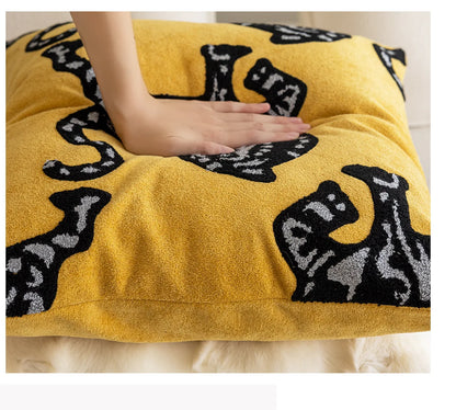 Yellow cushion with black cat patterns on a white surface. Modern minimalist embroidered pillow cover for living room decor.