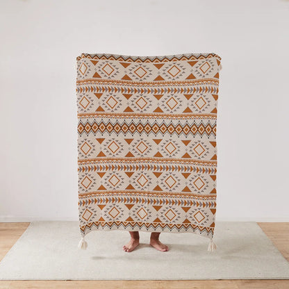 Bohemian Patterned blanket draped over a person on a light wooden floor with a white wall background
