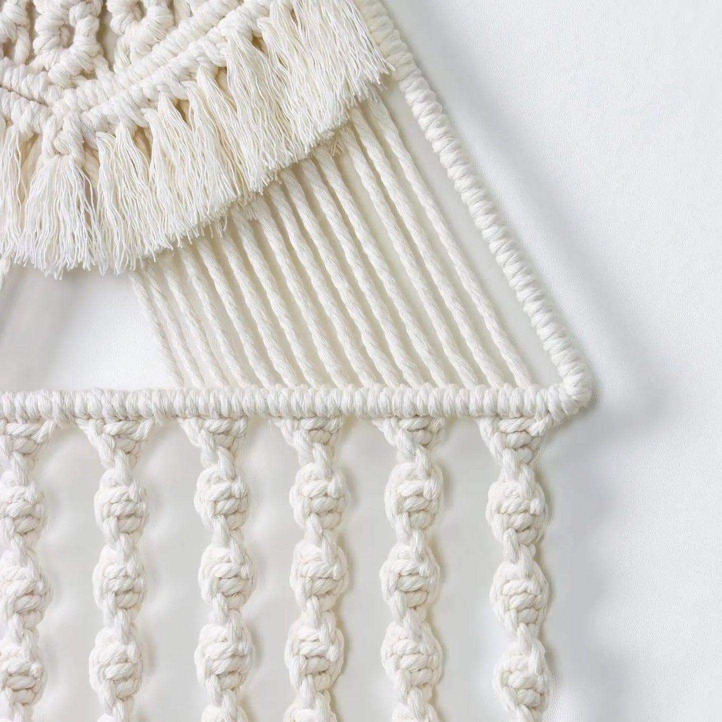 Close-up of a macrame wall hanging with intricate patterns and tassels on a light background. boho home decor, macrame wall hanging, triangle dream catcher, woven tapestry, handmade cotton wall decor, tassel wall hanging, bedroom door decor, housewarming gift, rustic bohemian art, boho apartment wall decor, neutral textile art