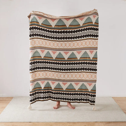 Patterned Bohemian blanket draped over a person on a wooden floor with a white wall background