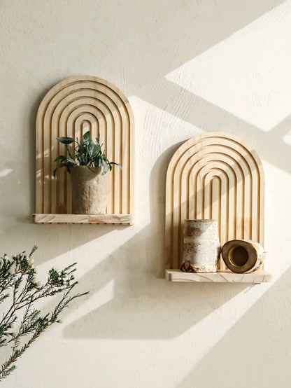 Two arch-shaped wall shelves with decorative items on a light background