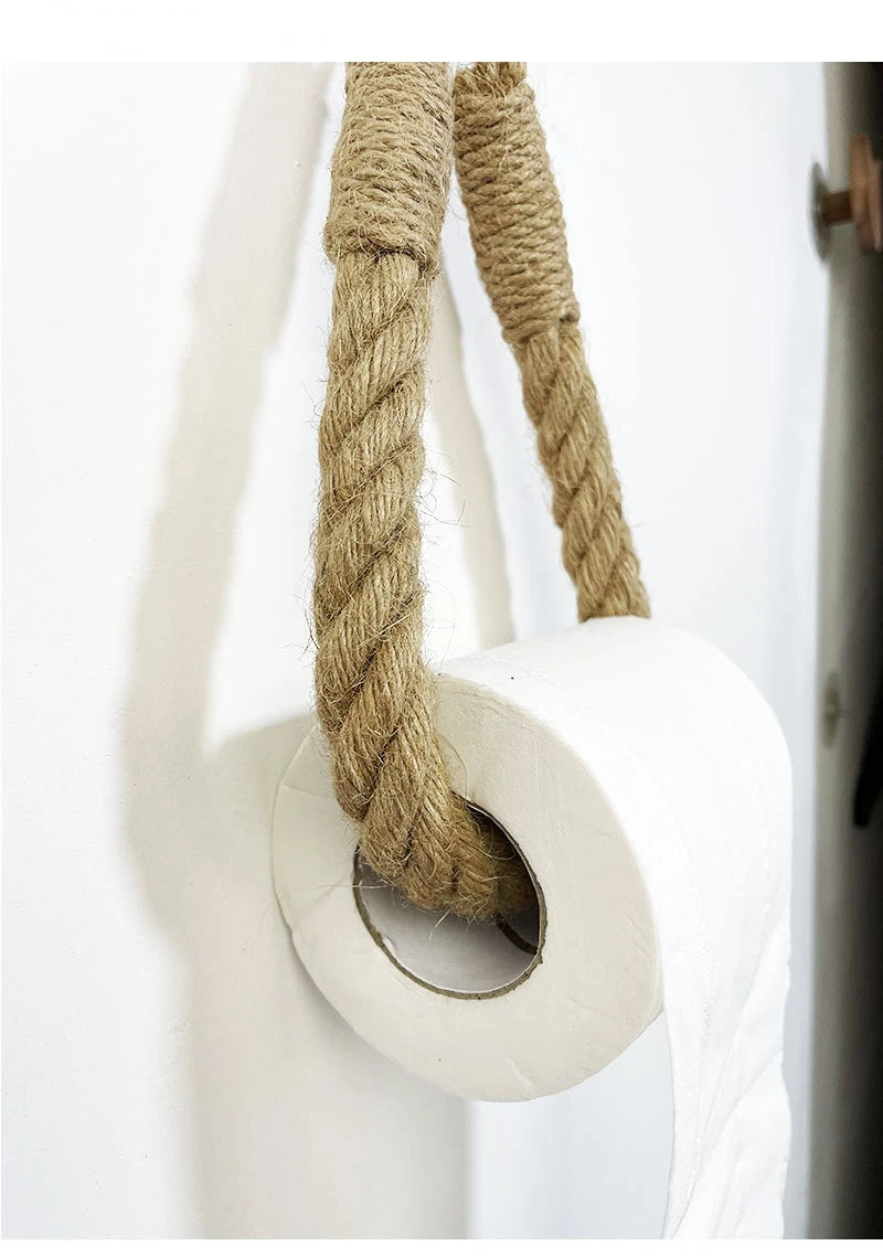 Close-up of a white door handle with a knotted rope on a white background. Boho rope toilet paper holder, nail-free wall mounted paper towel rack, rustic bathroom storage and decor accessory with wood and rope design
