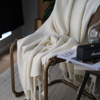 White knitted blanket draped over a chair with a blurred background