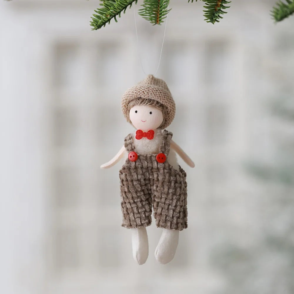 Decorative ornament of a boy in a hat and overalls hanging against a blurred natural background.