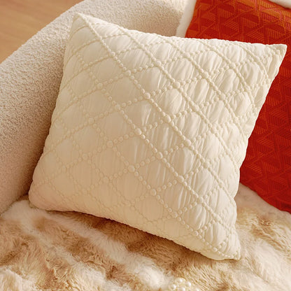 Quilted cream pillow on a textured surface with a red fabric background. Boho Home Decor. 