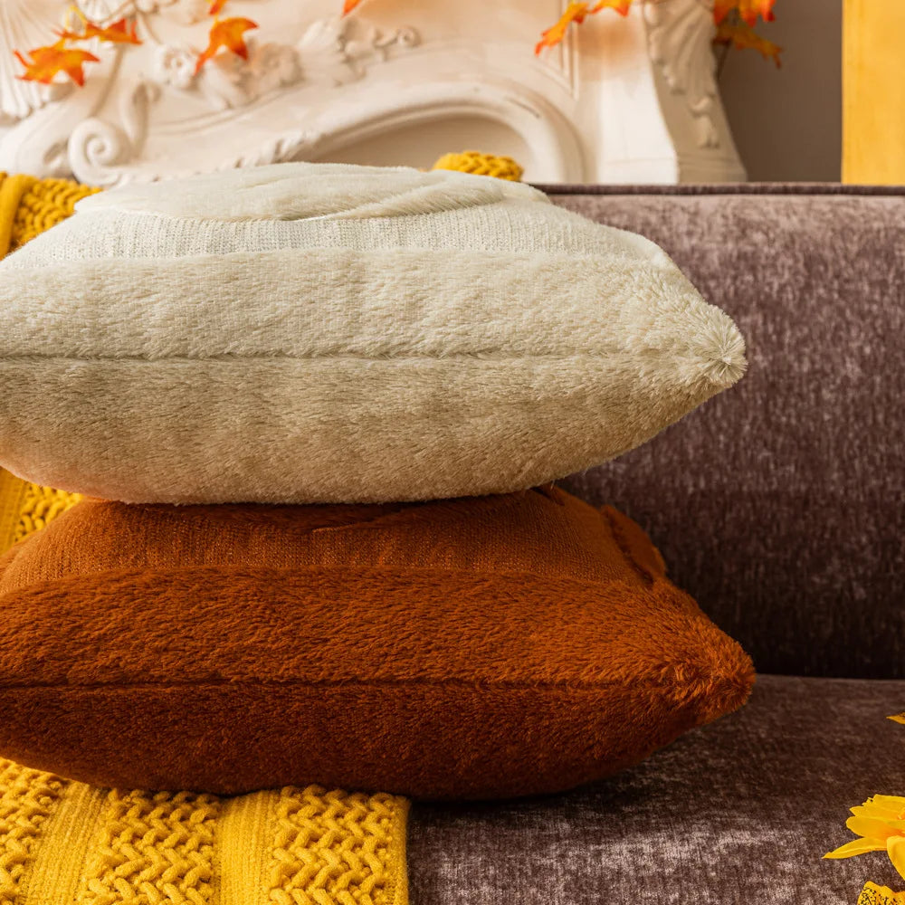 Stack of textured pillows in various colors on a sofa. Halloween pumpkin plush pillow cover for sofa and bed decor.