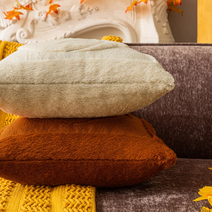 Stack of textured pillows in various colors on a sofa. Halloween pumpkin plush pillow cover for sofa and bed decor.