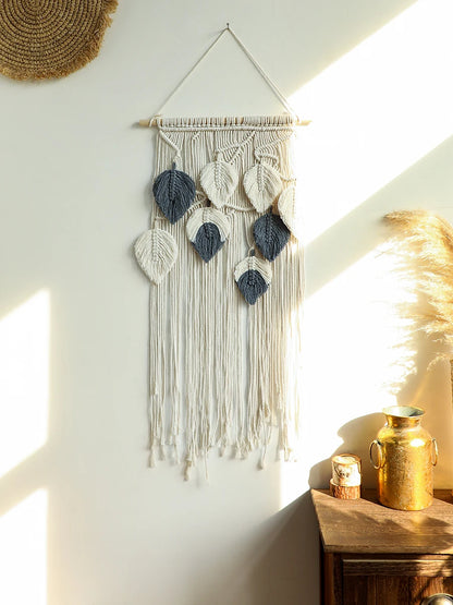 Macrame boho wall hanging with leaf patterns on a white wall with natural light.