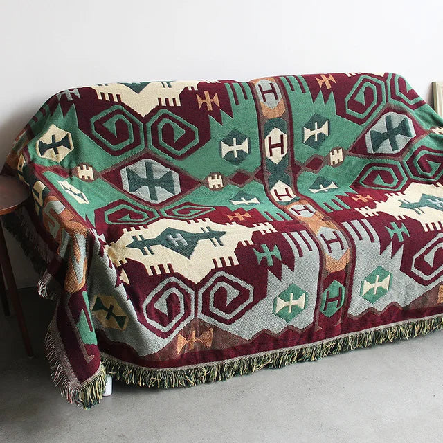 Colorful patterned blanket draped over a chair with a plain background. Mediterranean style woven cotton throw blanket boho home decor