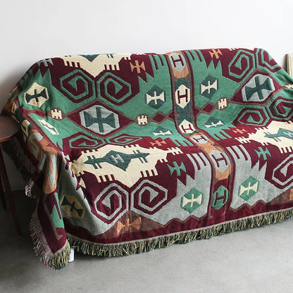 Colorful patterned blanket draped over a chair with a plain background. Mediterranean style woven cotton throw blanket boho home decor