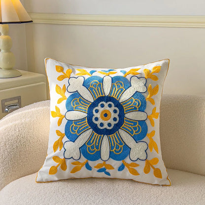 Decorative pillow with blue and yellow floral pattern on a beige couch.
