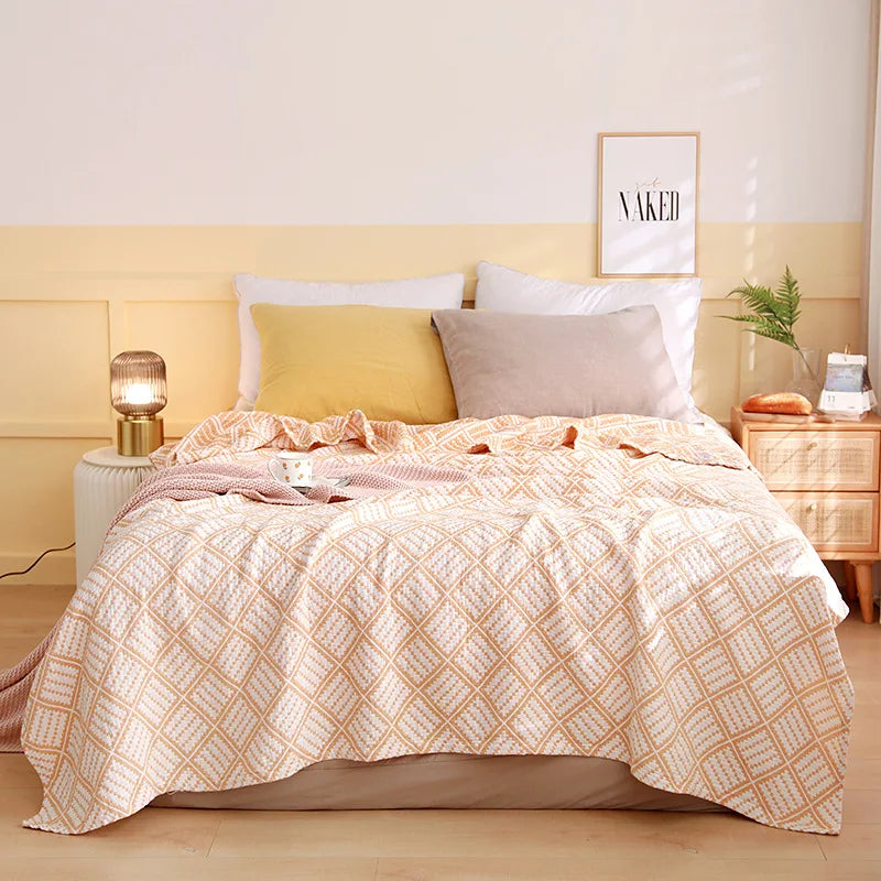 Bedroom with a bed featuring a patterned comforter, pillows, and nightstands. Boho Lightweight microfiber summer blanket for bed or sofa, cooling breathable throw for home, dorm, or office naps with geometric jacquard pattern.