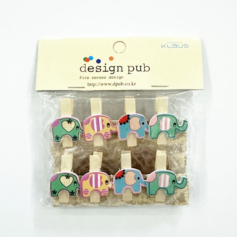 Packaged elephant-shaped wooden clips with colorful designs on a white background, branded 'Klaus' and 'design pub'.