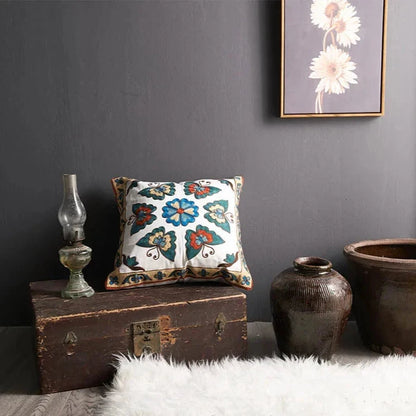 Decorative pillow with floral pattern on a wooden chest against a gray wall. floral embroidery on linen cotton cushion cover – boho home decor accent