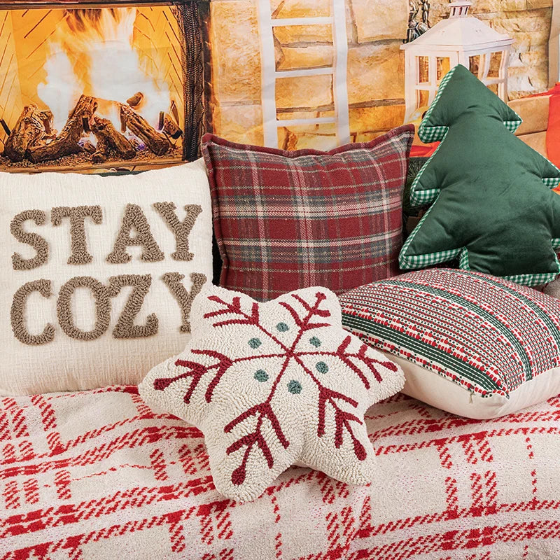 Decorative pillows with a 'Stay Cozy' pillow and festive patterns on a textured surface.