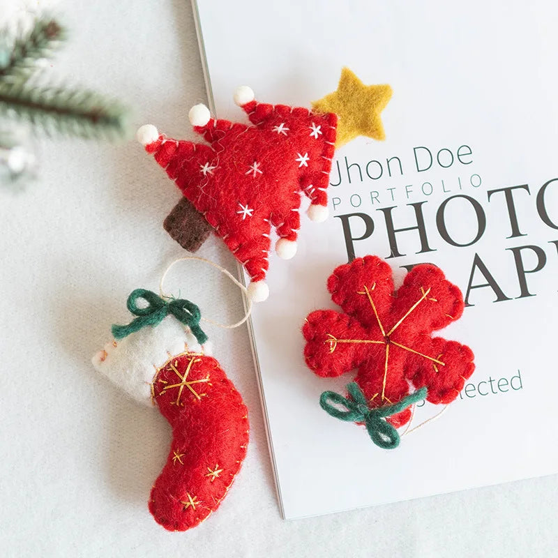 Red felt Christmas tree, star, and stocking decorations on a white surface with a photo album in the background.