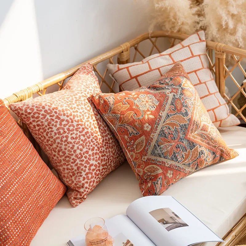 Decorative pillows on a wicker chair with a magazine open on a surface.