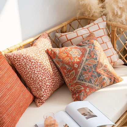 Decorative pillows on a wicker chair with a magazine open on a surface.