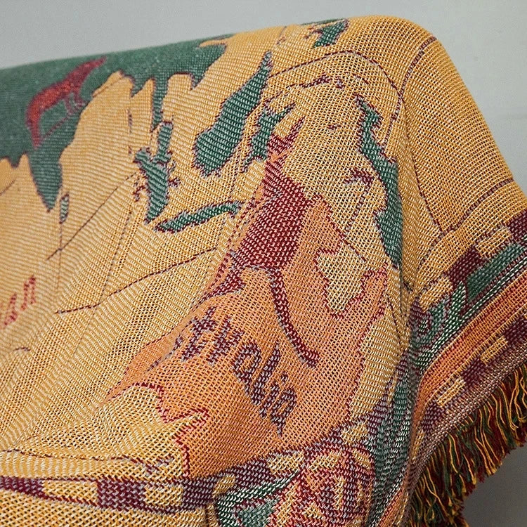 Close-up of a textured fabric with leaf patterns in yellow, green, and red. Travel-inspired cotton plaid bed cover and decorative boho blanket