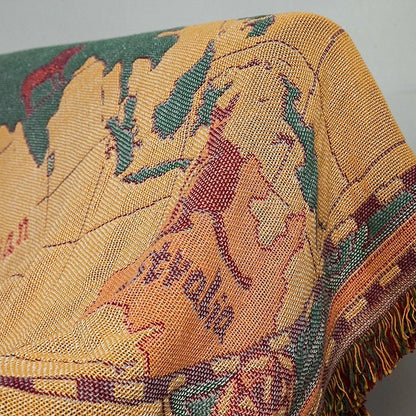 Close-up of a textured fabric with leaf patterns in yellow, green, and red. Travel-inspired cotton plaid bed cover and decorative boho blanket