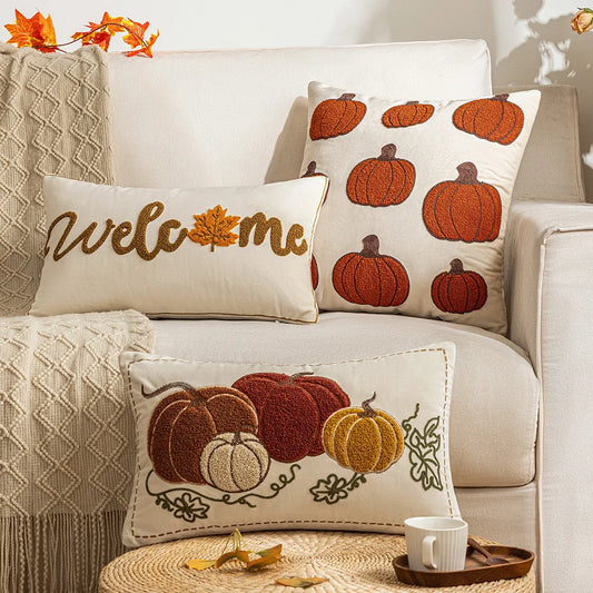Decorative pillows with pumpkin patterns on a beige sofa with autumn leaves. Autumn velvet embroidered pumpkin pillow cover, Nordic-style decorative cushion for sofa, bed, and fall boho home decor