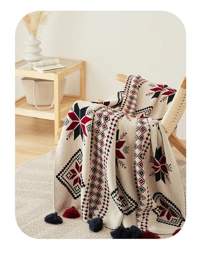 Patterned boho winter blanket draped over a chair with a wooden side table in the background