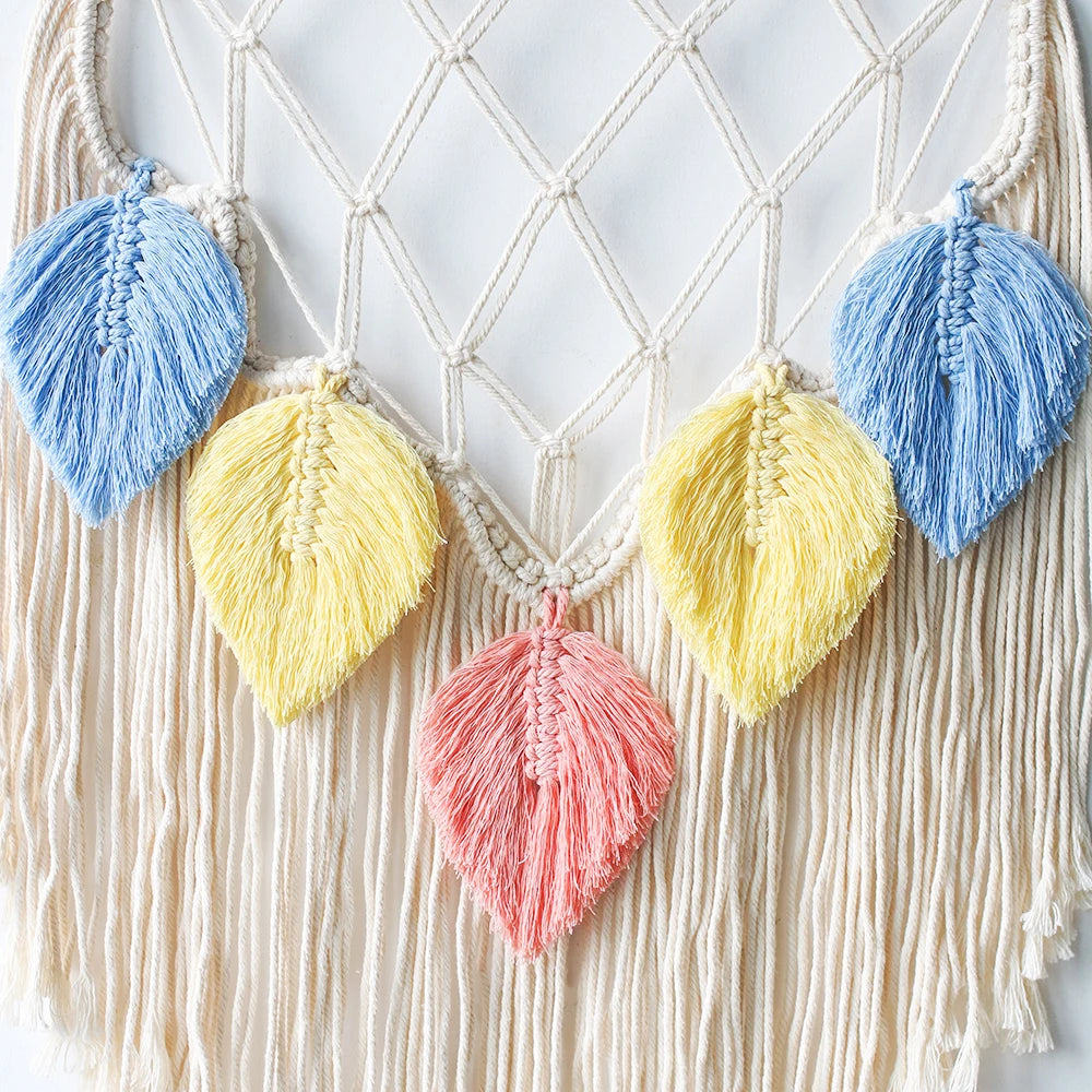 Macrame wall hanging with colorful yarn leaves on a textured white background