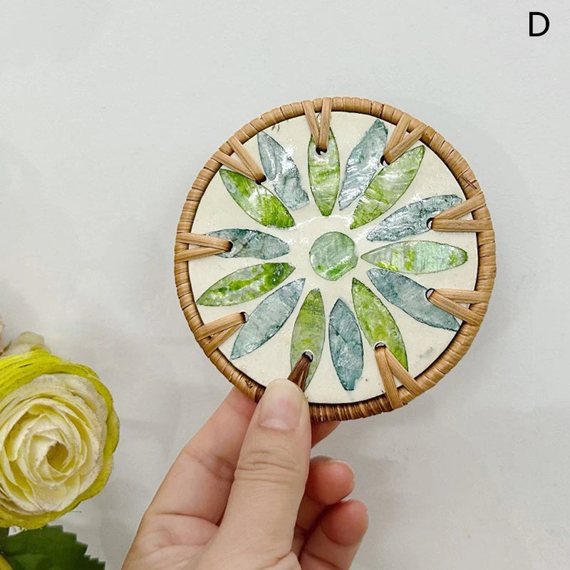 Hand holding a circular boho coaster with green leaf patterns on a light background