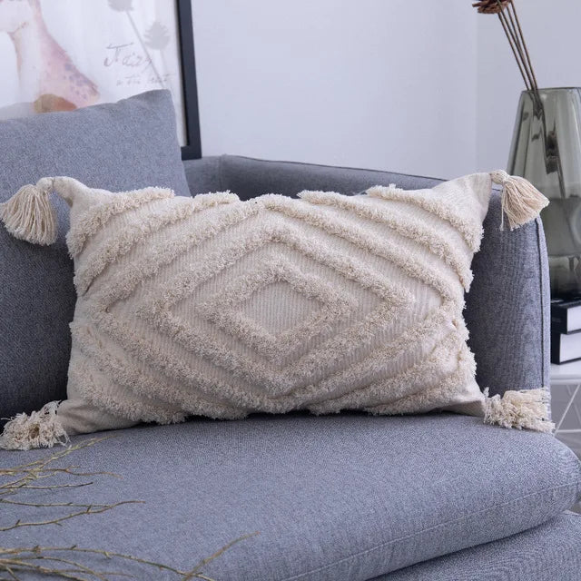 Textured pillow with tassels on a gray sofa in a living room setting