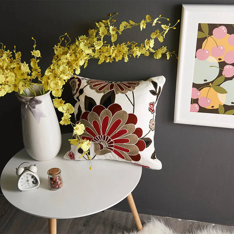 Decorative pillow on a table with yellow flowers and a framed picture on a dark wall. floral embroidery on linen cotton cushion cover – boho home decor accent