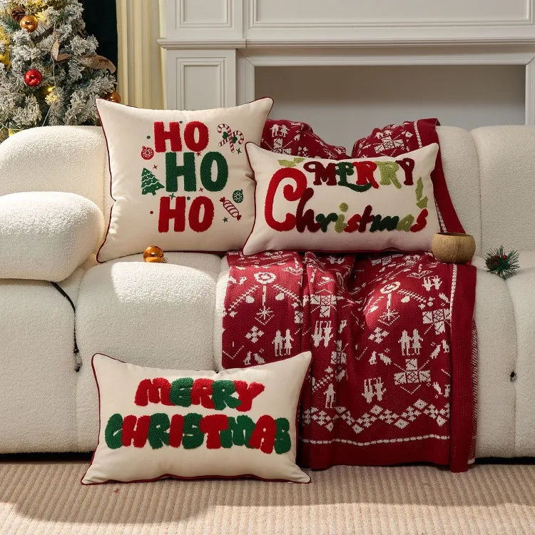 Decorative Christmas pillows with Ho ho Ho, Merry Christmas and blanket on a sofa with a festive background.