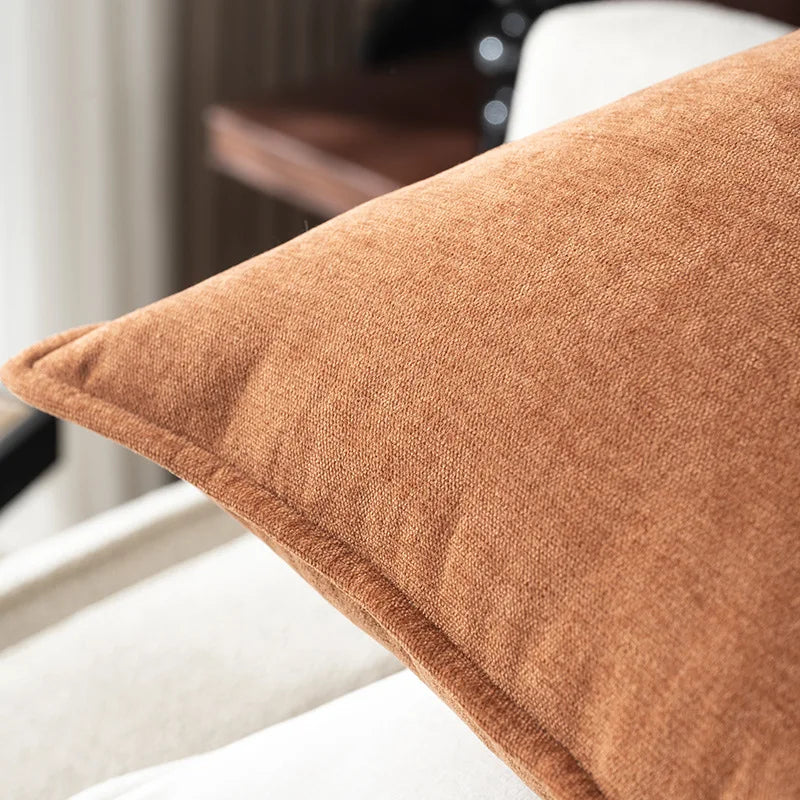 Brown textured pillow on a white chair with a blurred background