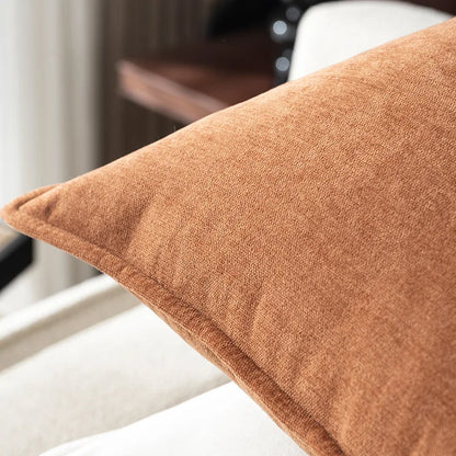 Brown textured pillow on a white chair with a blurred background